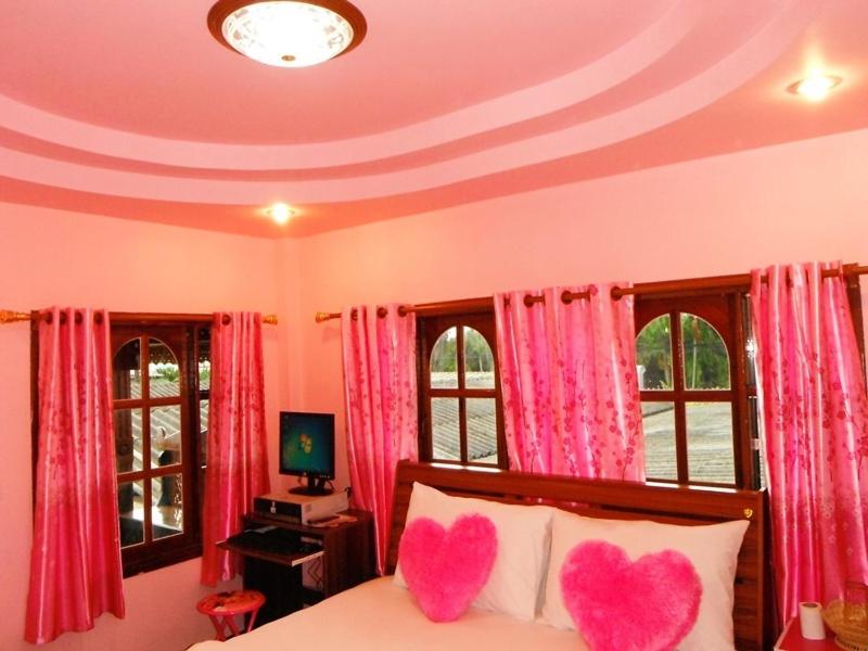 1 dormitorio con 2 corazones rosados en una cama en Suksomjai Hotel, en Rayong