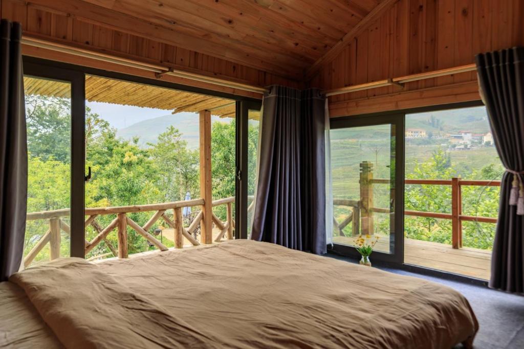 a bedroom with a bed and large windows at De Amor House & Coffee in Sa Pa