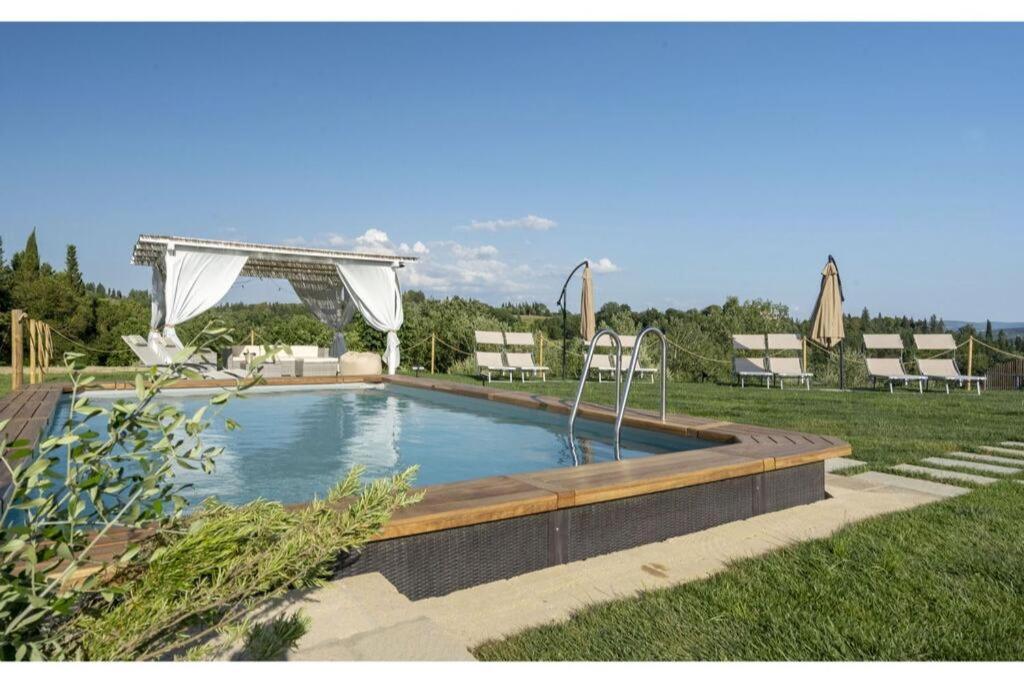 una piscina en un patio con sillas y sombrillas en Villa Zara, en Palaia