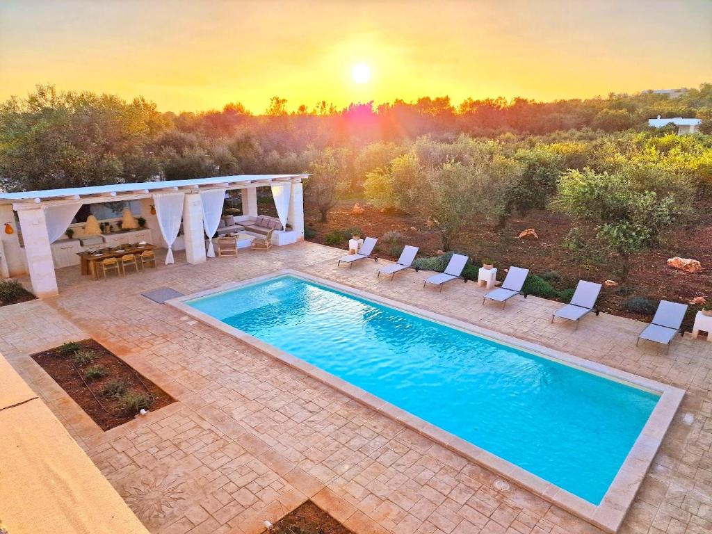 a pool with chairs and a sunset in the background at Trulli Tramontana - private pool in Ostuni