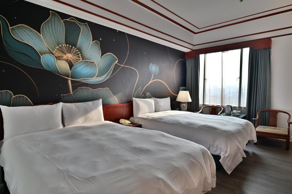 two beds in a hotel room with a flower on the wall at T Hotel in Taichung