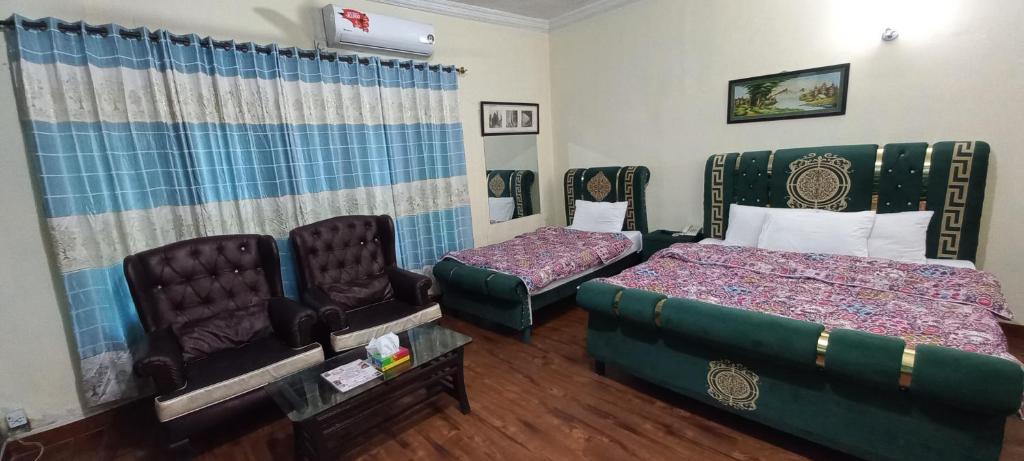 a room with two beds and chairs in it at ORION INN Guest House F-7 Islamabad in Islamabad