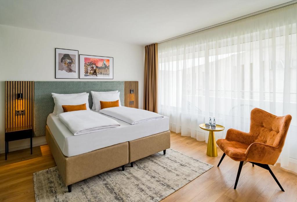 a bedroom with a bed and a chair at Aspire Palais Recklinghausen, Trademark Collection by Wyndham in Recklinghausen