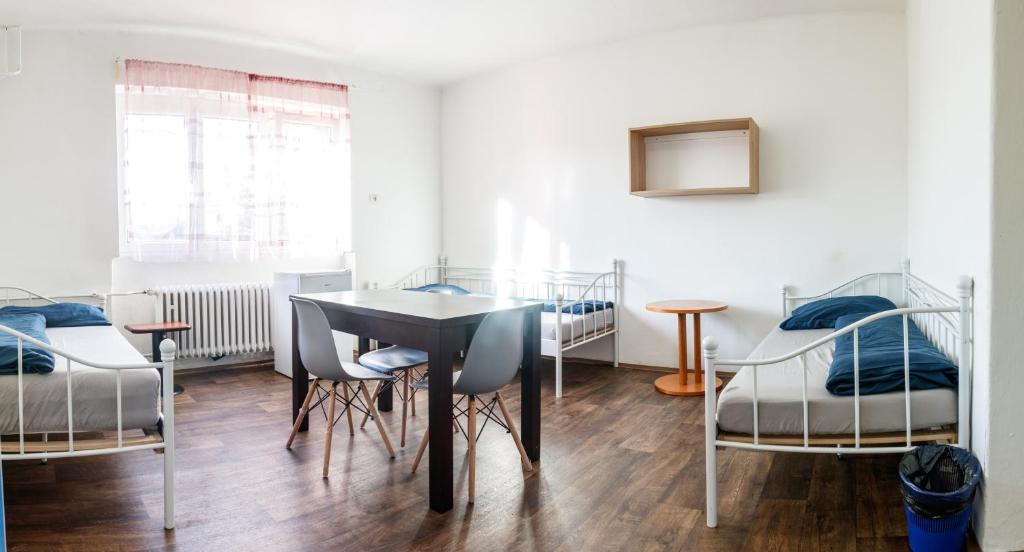Moravská OstravaにあるUbytovna Šalamounのベッド3台、テーブル、椅子が備わる客室です。