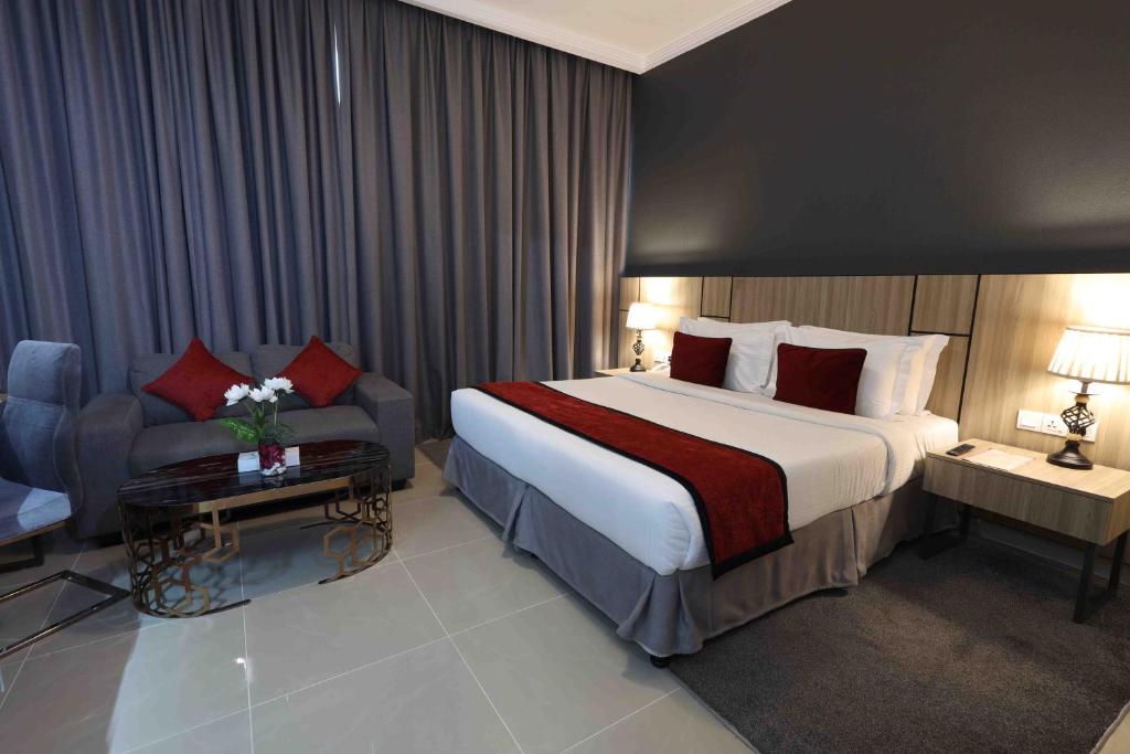 Fortis Hotel Fujairah في الفجيرة: غرفة فندقية بسرير كبير واريكة