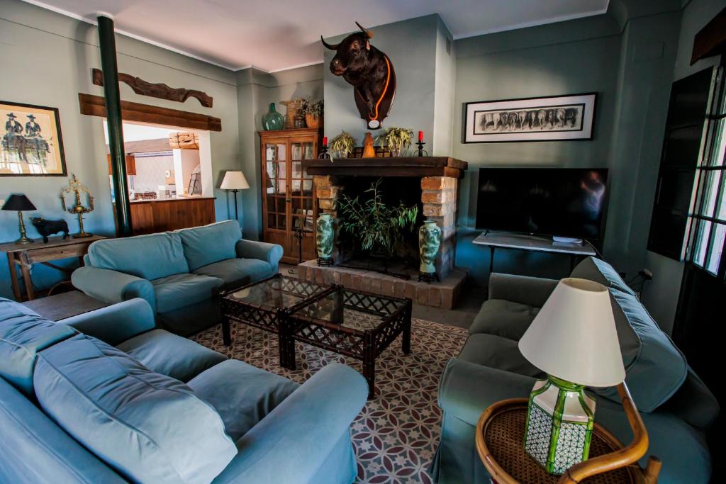 uma sala de estar com sofás azuis e uma lareira em Habitaciones El Rocio em El Rocío