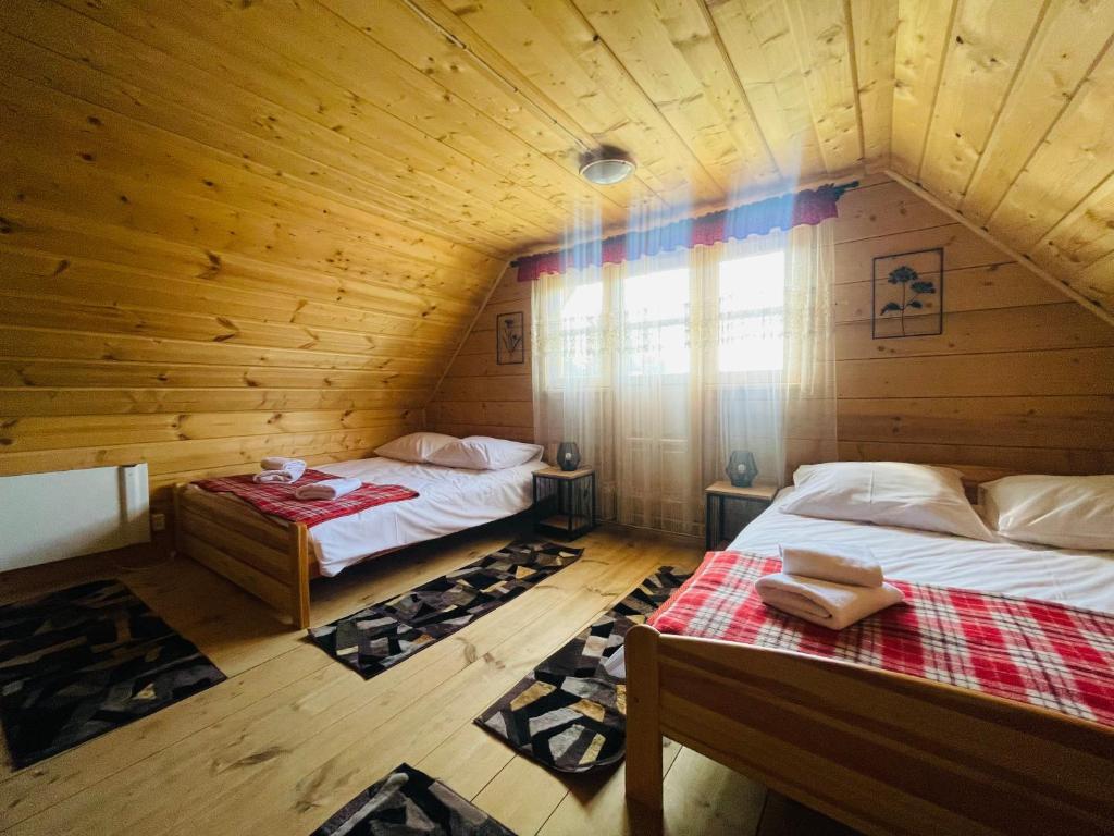 - une chambre avec 2 lits dans une cabane en bois dans l'établissement Bacówka u Bobika, à Waksmund