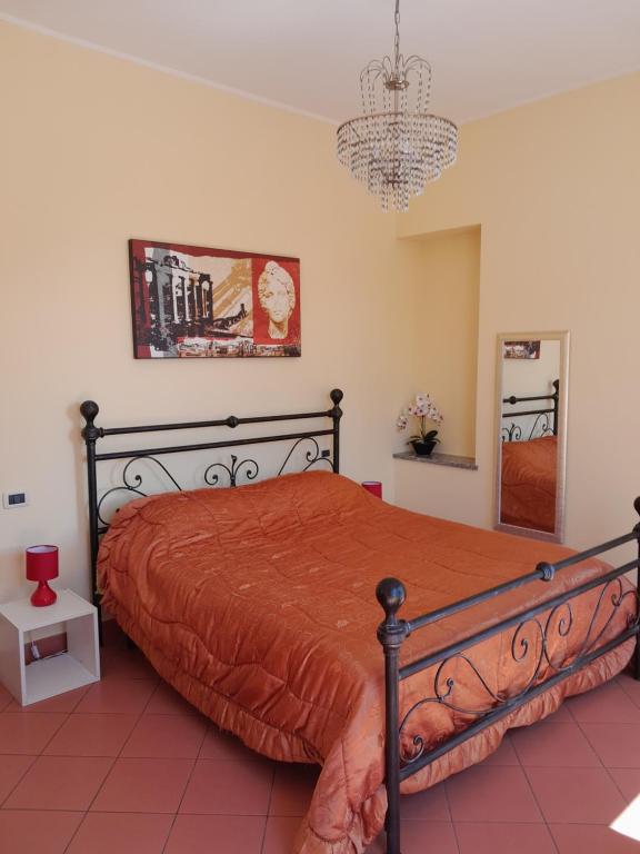 ein Schlafzimmer mit einem Bett mit einer orangefarbenen Tagesdecke und einem Kronleuchter in der Unterkunft "B&B Sans égal", con camere private e appartamenti al piano terra a Biella in Biella