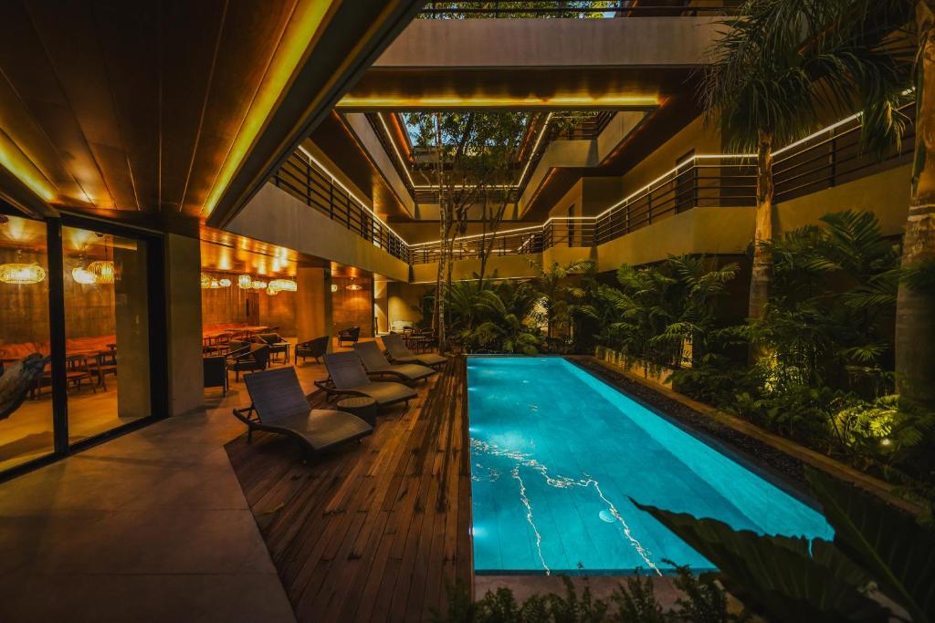 uma piscina interior num edifício com cadeiras e árvores em Piece Lio Resort from Japan em El Nido