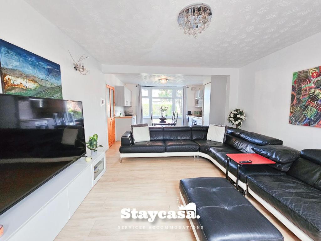 un soggiorno con divano in pelle nera e TV a schermo piatto di Inviting & Spacious 6bdr Home With Free Parking! a Manchester