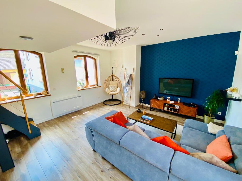 a living room with a blue couch and a tv at Un petit écrin au cœur du vignoble alsacien in Mittelwihr