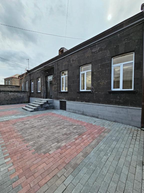 un edificio de ladrillo con ventanas blancas y un patio de ladrillo en Shahumyan 98 Guest house, en Gyumri