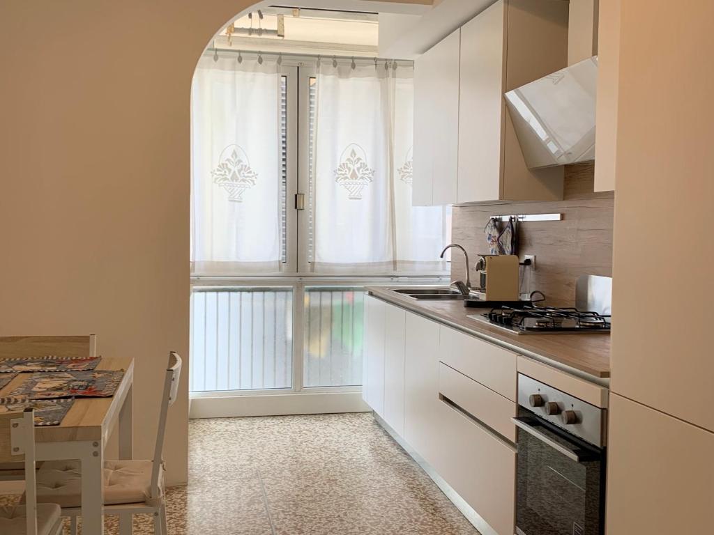 a kitchen with white cabinets and a table and a window at Appartamento Jesolo Piazza Drago in Lido di Jesolo
