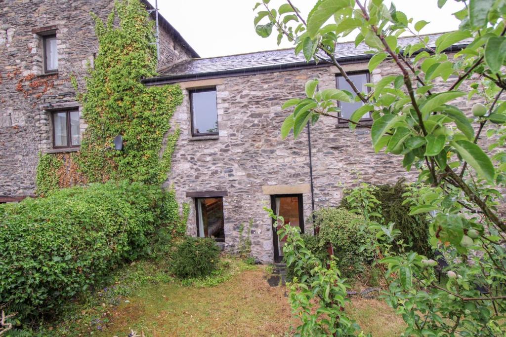 - une ancienne maison en pierre avec du lierre dans l'établissement Barn Owl Cottage, Lindale, à Lindale