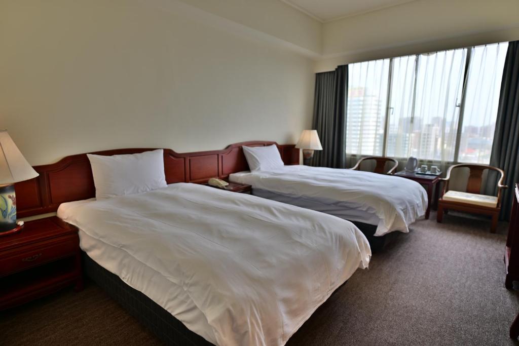 a hotel room with two beds and a large window at T Hotel in Taichung