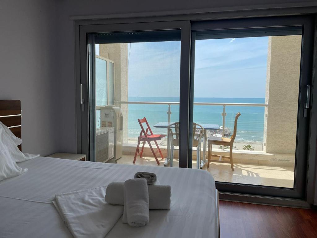 a bedroom with a bed and a view of the ocean at Blumont Aparthotel Durres in Durrës