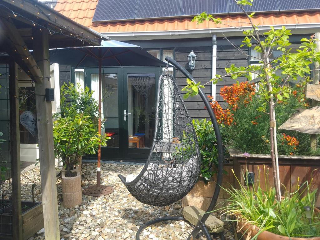 a hammock hanging in front of a house at Tiny House Tulp in Oudesluis