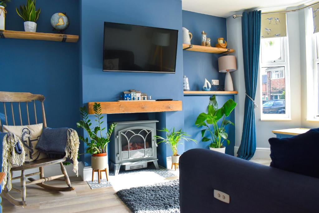 sala de estar con paredes azules y chimenea en Avocet - Suffolk Coastal Escapes, en Pakefield