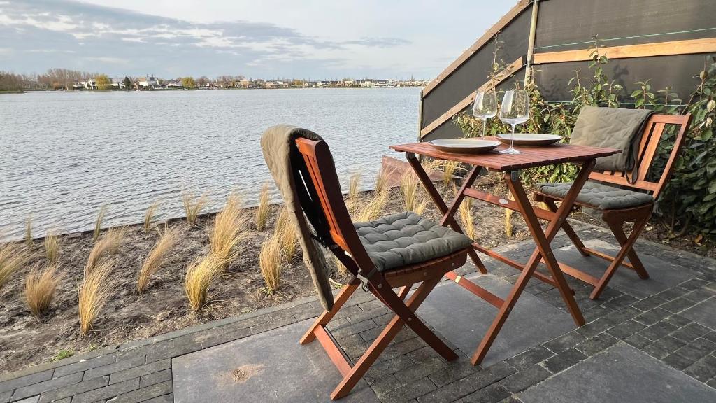 einen Tisch und Stühle neben dem Wasser in der Unterkunft Studio Lakeview in Goes