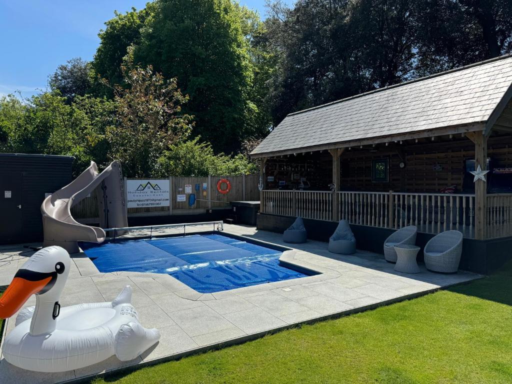 a swimming pool with a slide and a swan at Incredible summer winter 32c heated pool hot tub bar in Kent