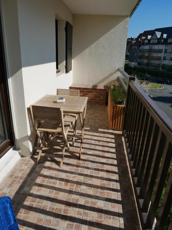 a patio with a wooden table and chairs on a balcony at Plage Cabourg 7bis in Cabourg
