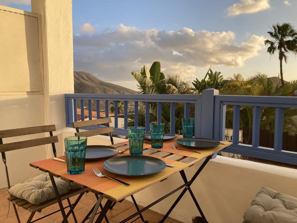 a wooden table with plates and glasses on a balcony at Chayofa Blue in Chayofa