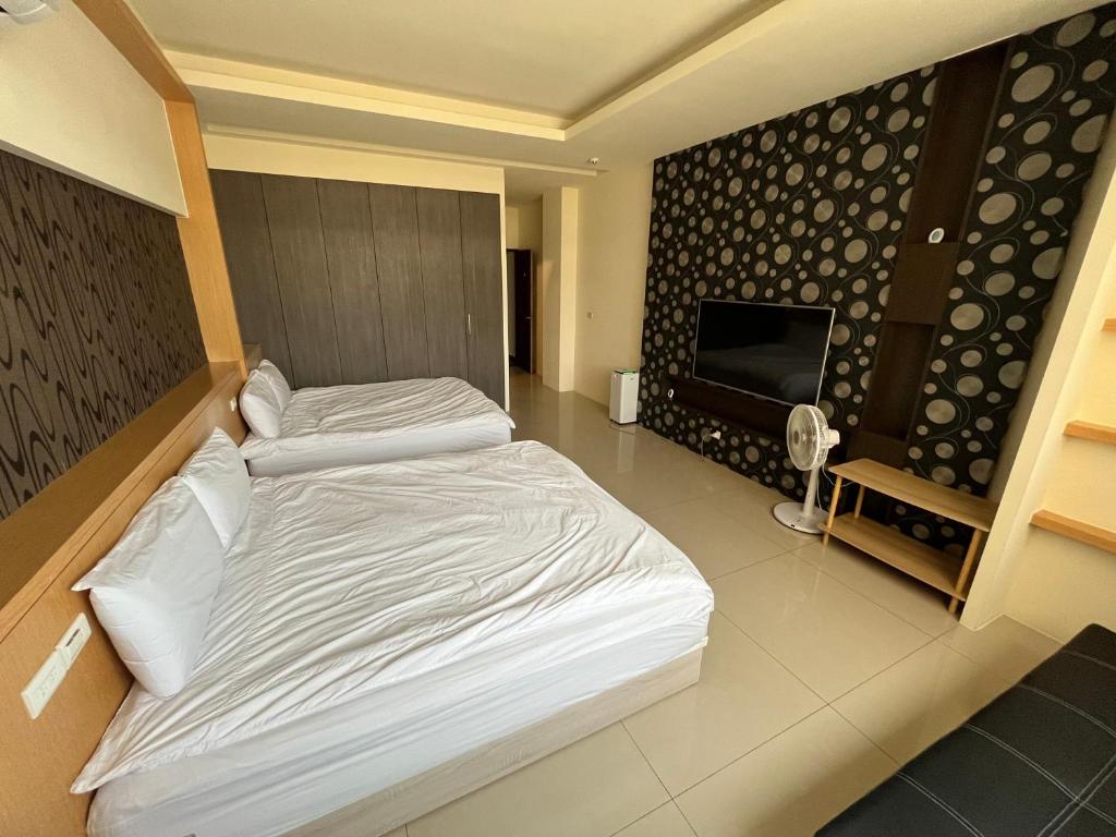 a bedroom with two beds and a flat screen tv at 鹿港蕎禾旅宿 in Lukang