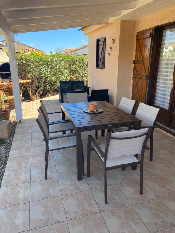 Une table à manger et des chaises sont disponibles sur la terrasse. dans l'établissement Maison avec jardin Résidence Horizon Bleu Vendres, à Vendres