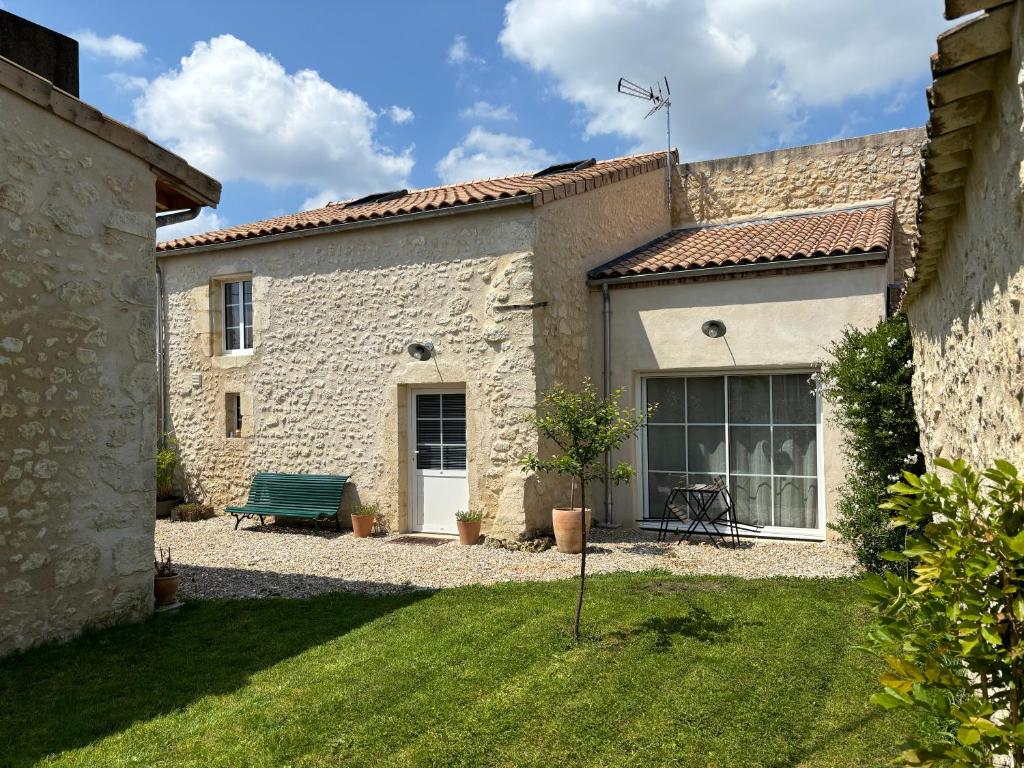 a stone building with a green bench in a yard at Château La Fon du Berger in Saint-Sauveur