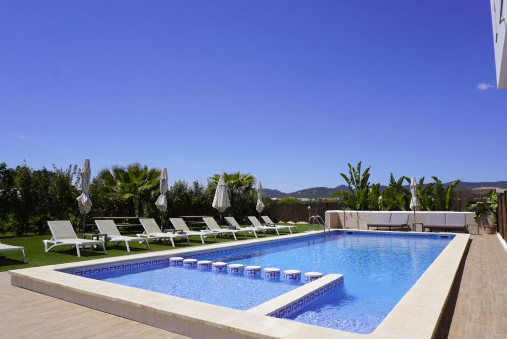 a swimming pool with chaise lounge chairs next to a resort at Los Escondidos Ibiza in Playa d'en Bossa