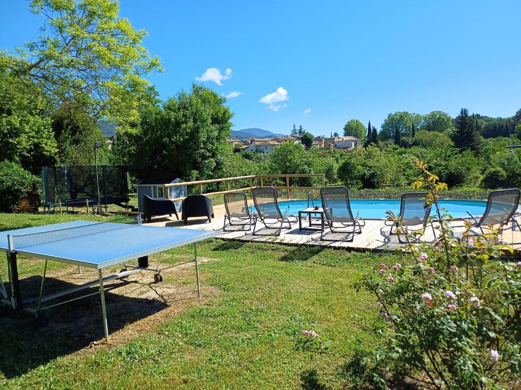 una mesa de ping pong y sillas junto a una piscina en La ferme d'Andréa au milieu des vignes à 3min à pied du centre piscine chauffée climatisation, en Lourmarin