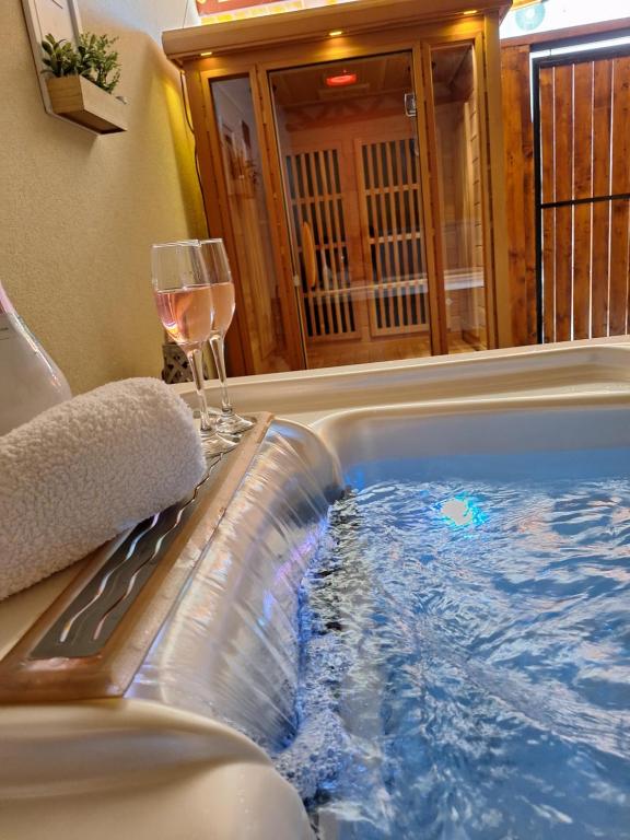 a hot tub with a glass of wine and a glass of water at Várfal apartman II in Eger