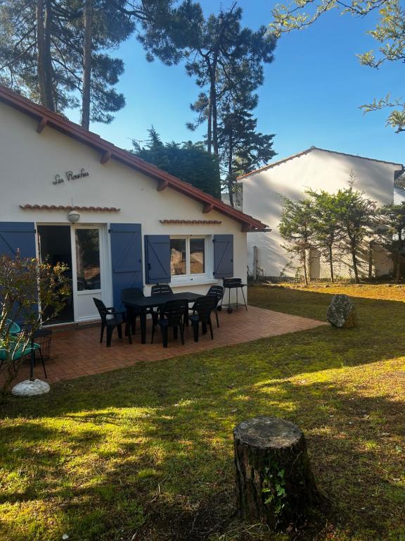 une maison avec une table et des chaises dans une cour dans l'établissement Les grillons d’Eden, à Saint-Jean-de-Monts