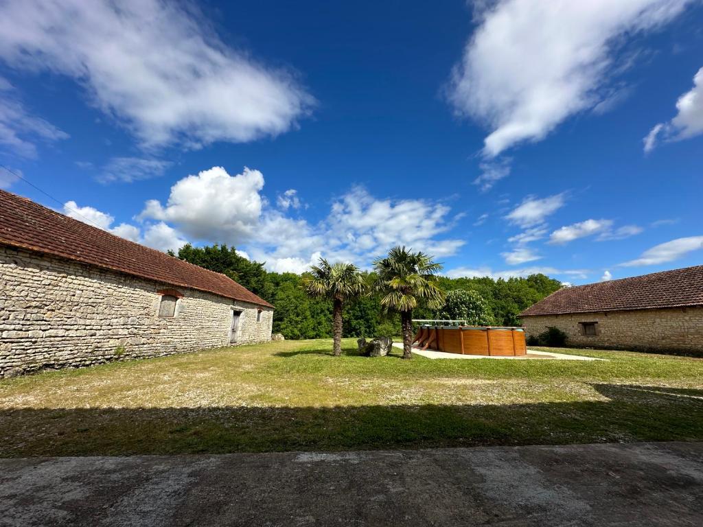 The charming private Farmhouse at La Grenouillére في Puyréaux: ساحة بها نخلتين ومبنى