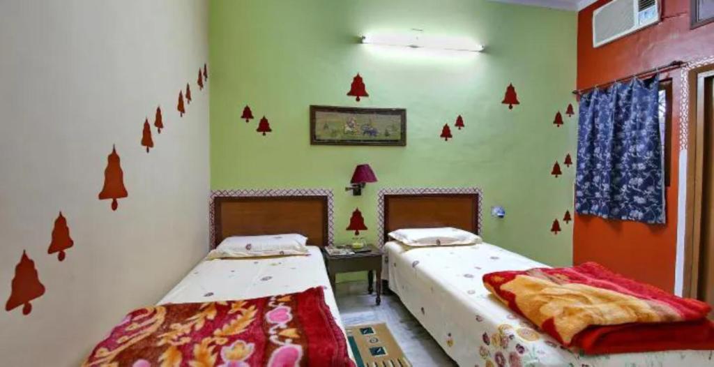 two beds in a room with red decals on the walls at Goroomgo Hotel Casa Di William Khajuraho in Khajurāho