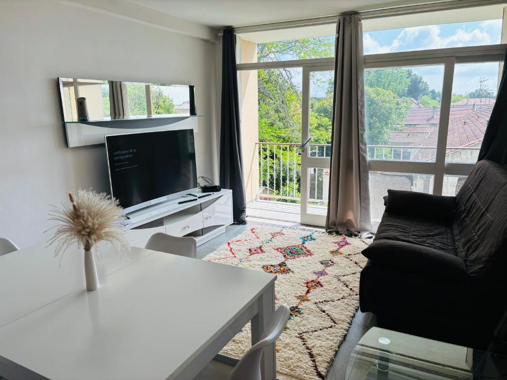 un salon avec une télévision, un canapé et une table dans l'établissement Appart. BAILA, proche de Bordeaux et St Emilion, à Libourne