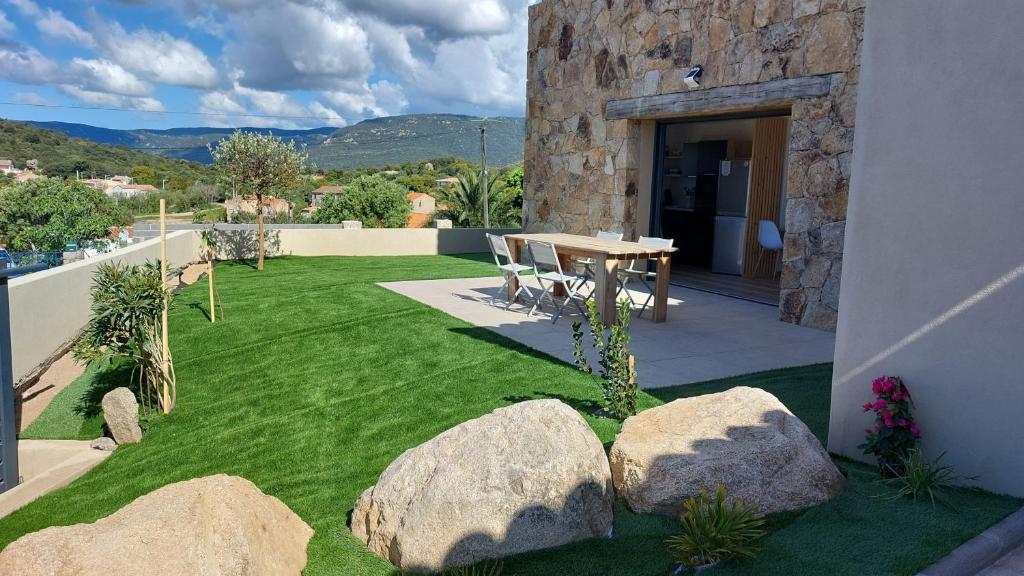 un jardin avec des rochers et une table sur une pelouse dans l'établissement Maison proche de la mer, à Pianottoli-Caldarello