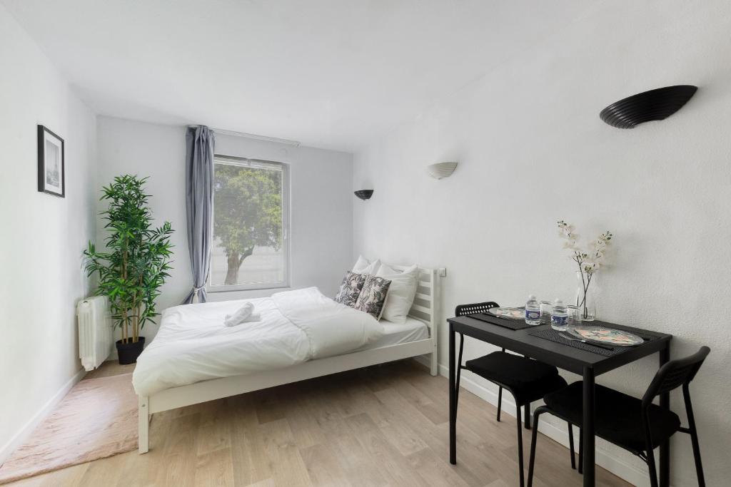 a white bedroom with a bed and a table at ADAGIO Access - PARIS LA DEFENSE in Courbevoie
