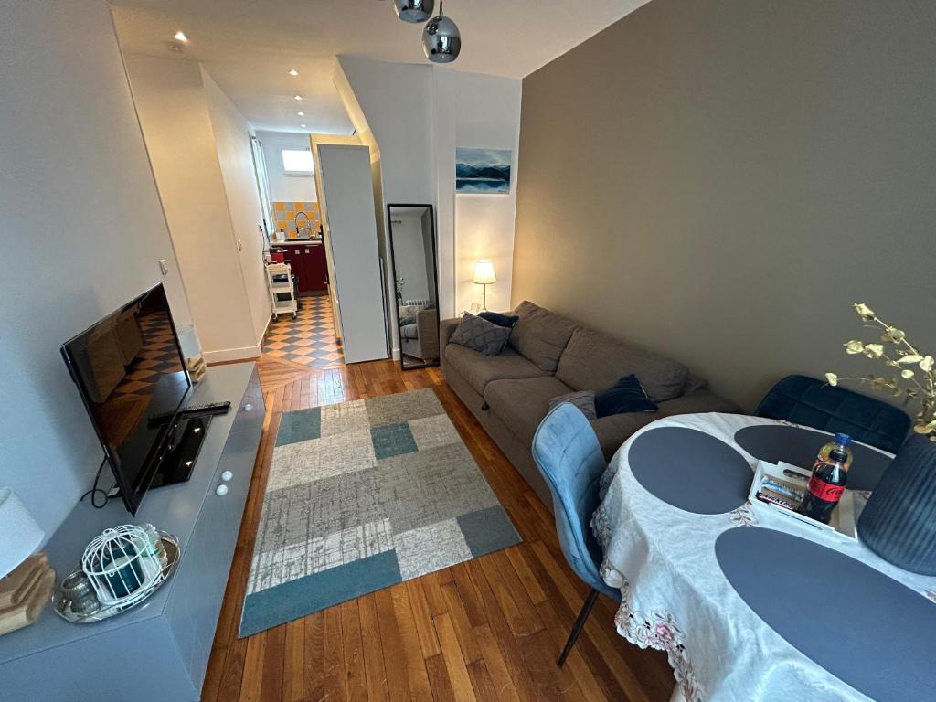 uma sala de estar com um sofá e uma mesa em Appartement cosy, Bois de Vincennes-porte de Paris em Saint-Mandé