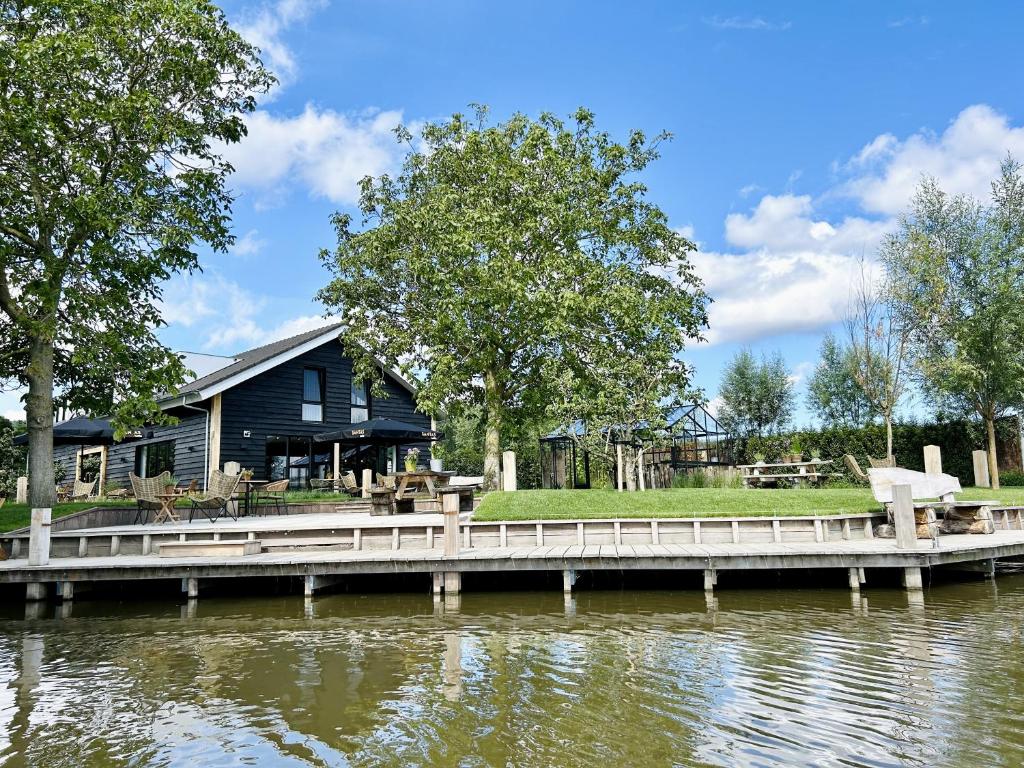 a house with a dock next to a body of water at Hoeve BuytenHout in Delft