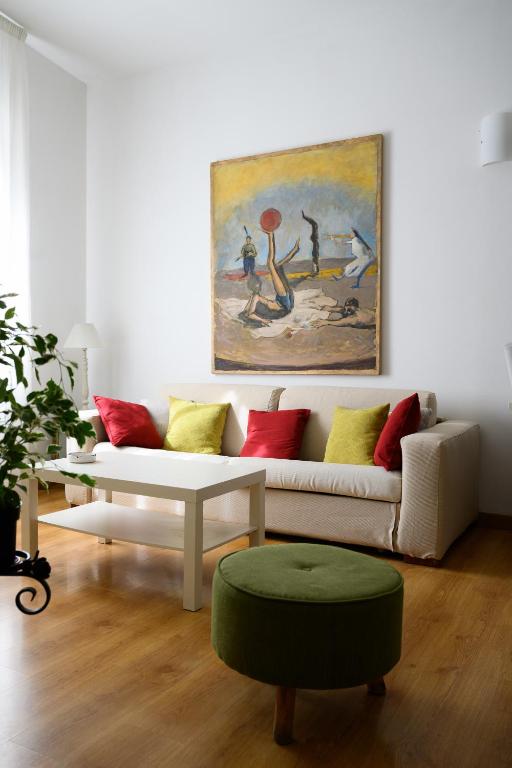 a living room with a white couch and a painting at Piazza Roma Apartment in Ascoli Piceno