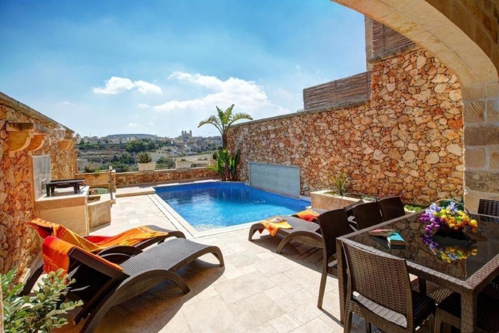 een patio met een zwembad en een tafel en stoelen bij Villa Cara in Għarb