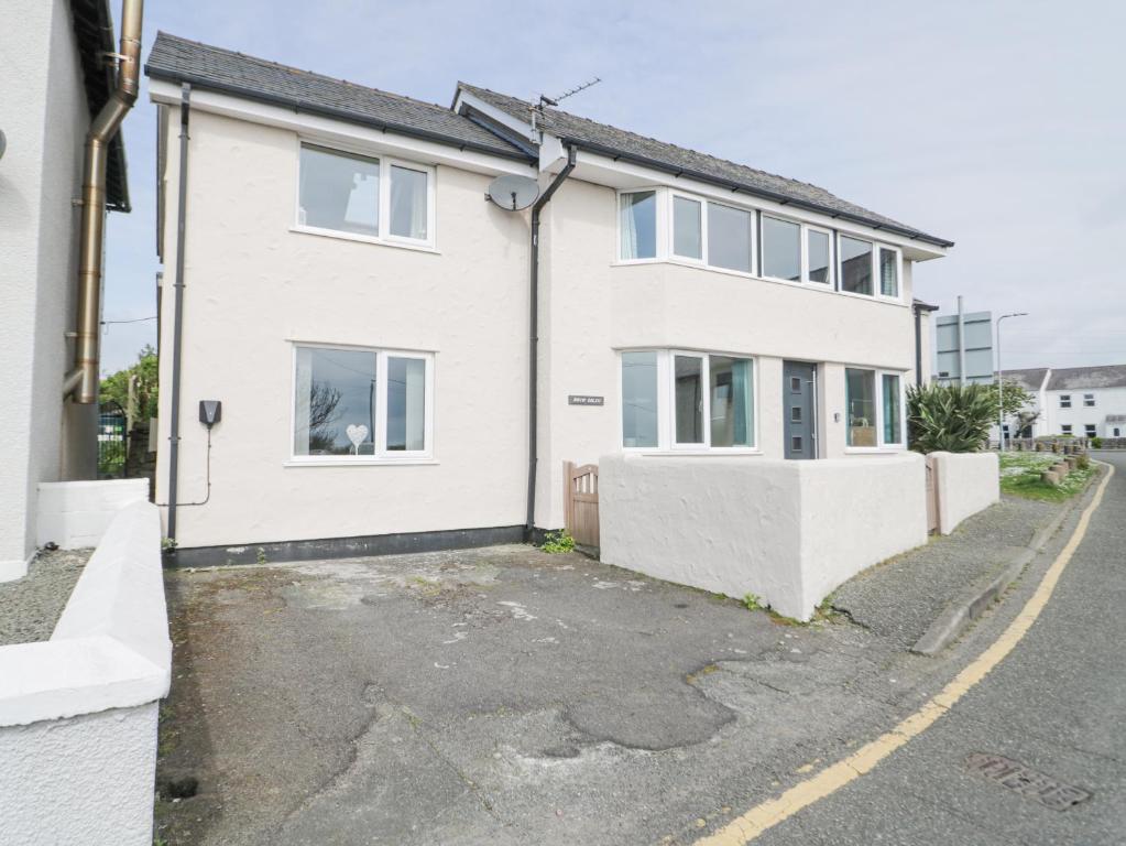 a white house with a parking lot at Bryn Goleu in Moelfre