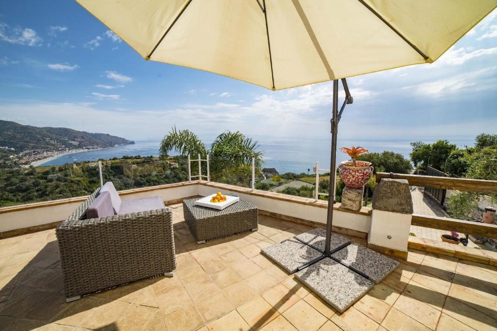 um pátio com um guarda-sol, cadeiras e uma mesa em Gästezimmer für 2 Personen ca 20 qm in Taormina, Sizilien Ostküste von Sizilien em Taormina