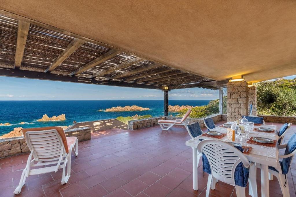 een patio met een tafel en stoelen en de oceaan bij Ferienhaus in Costa Paradiso mit Grill, Terrasse und Garten in Costa Paradiso