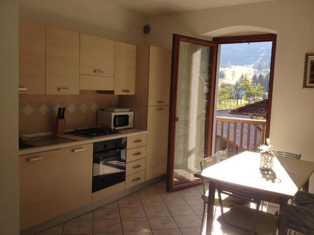 cocina con mesa y balcón con vistas. en Appartement in Tiarno Di Sotto en Tiarno di Sotto