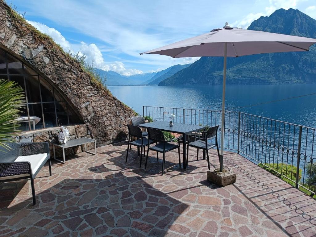 een patio met een parasol en een tafel en stoelen bij Studio Zu - Lakeside Apartment in Riva di Solto