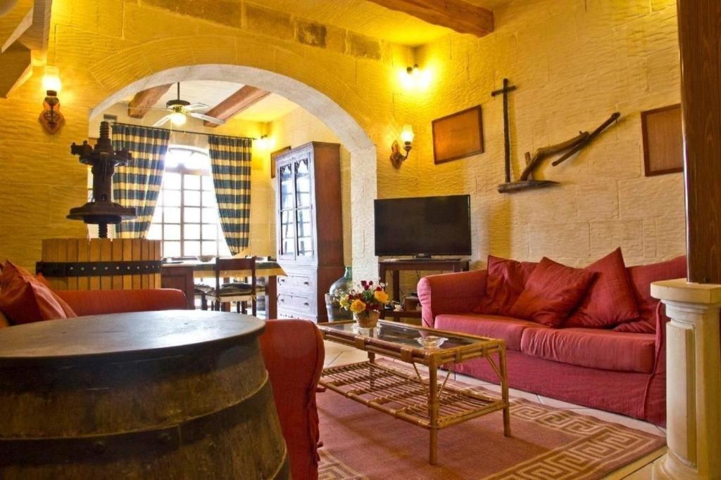 un soggiorno con divano rosso e tavolo di Villa Harruba a Xagħra