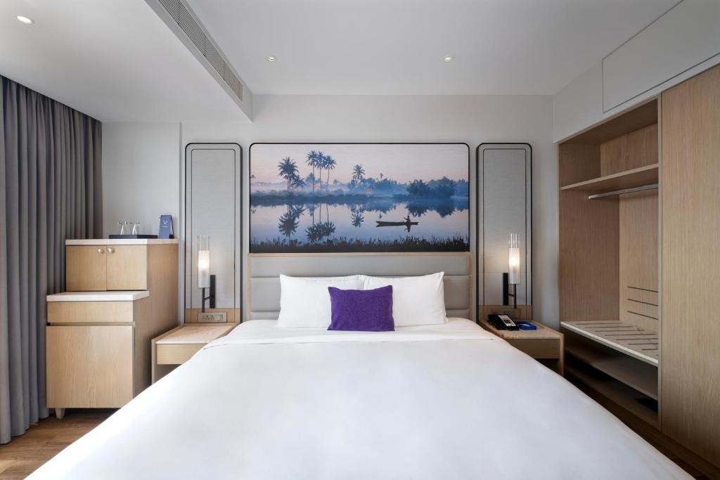 1 dormitorio con 1 cama blanca grande con almohada morada en Vivanta Goa, Miramar en Panaji
