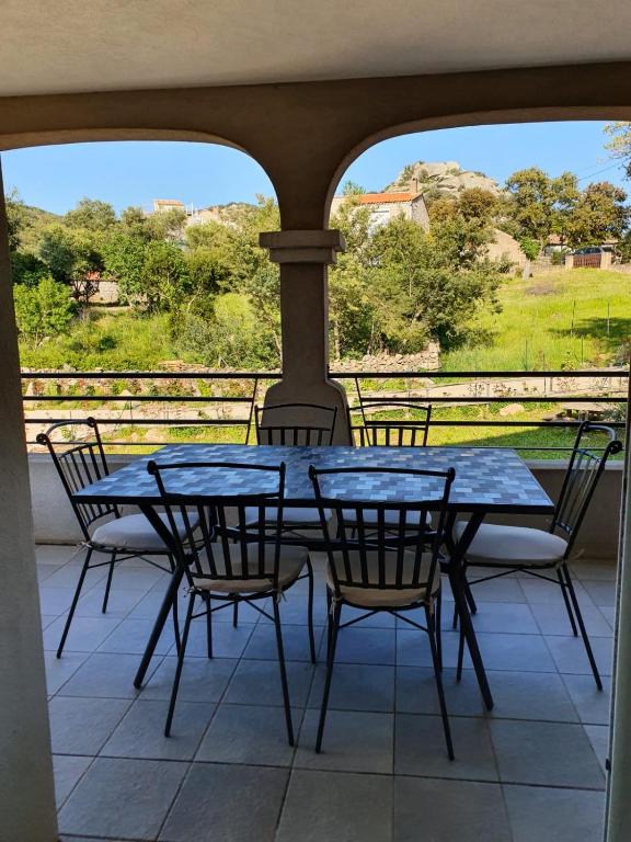 - une table bleue et des chaises sur une terrasse couverte avec vue dans l'établissement Appartement T4 Notta Bene - entre mer et montagne, à Porto-Vecchio